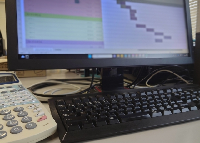 エクセル画面が表示されたパソコンと電話