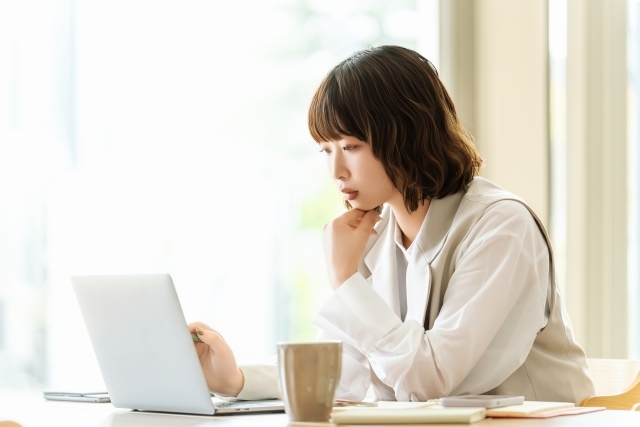 パソコンを見ながら考える女性