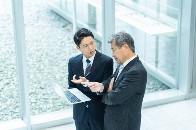 パソコンを見ながら話し合う男性社員