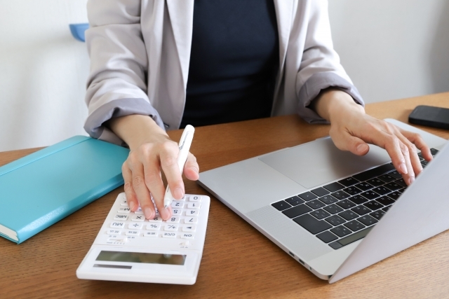 PCと計算機を使用する女性