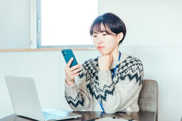 スマホを見て悩む女性