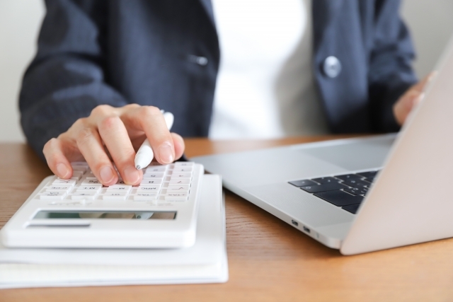 電卓とパソコンを使っている人