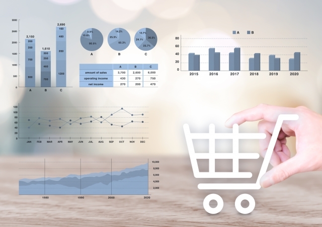 さまざまなグラフとショッピングカートを持つ人の手