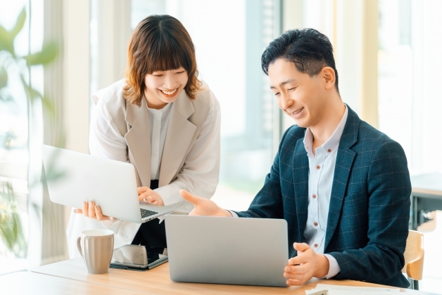 パソコンを見ながら話し合う会社員