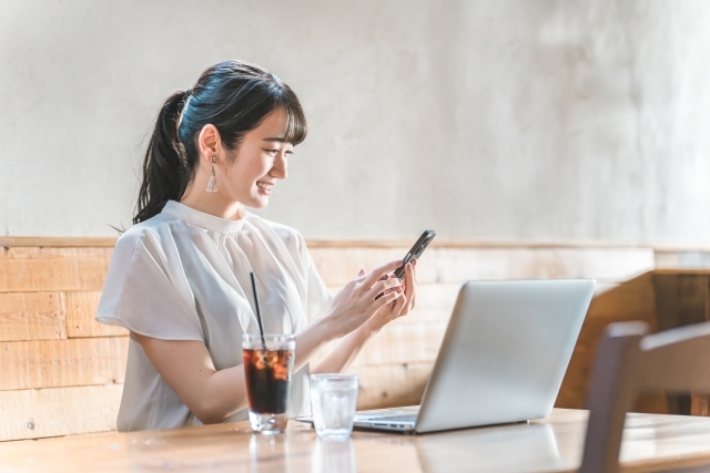 仕事中にスマートフォンを見ている女性