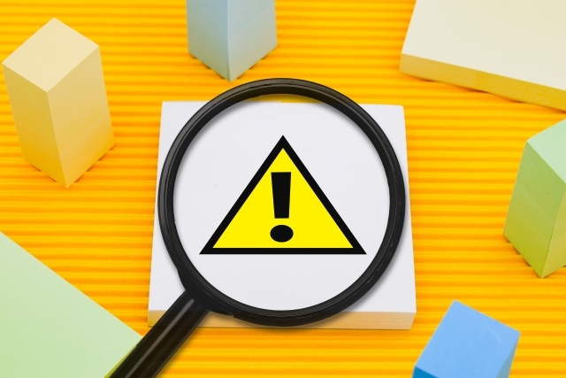 注意マークの上に置かれた虫眼鏡