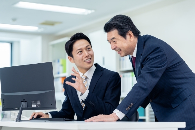 パソコンの前で話す男性社員たち