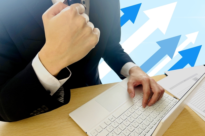 右上がり矢印の背景にこぶしを握るビジネスマン