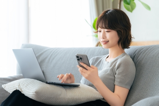 ソファでスマートフォンを操作する女性
