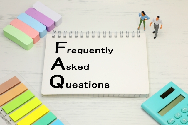 FAQの文字が書かれたメモと人形、電卓、付箋