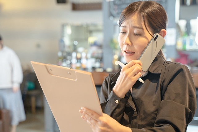 資料を見ながら電話で発注する女性