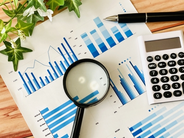 虫眼鏡とグラフ、電卓、ペン