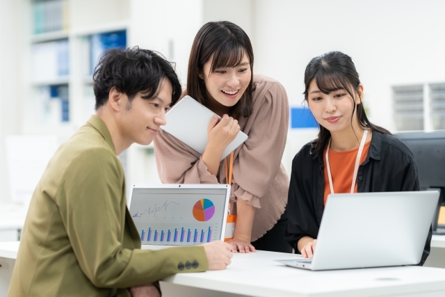 ノートパソコンを見ながら話し合う男女